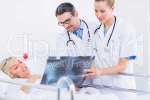 Doctors showing x-ray to patient in bed