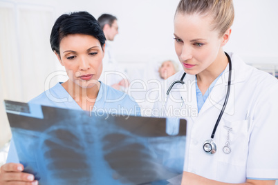 Doctors examining x-ray with patient in background