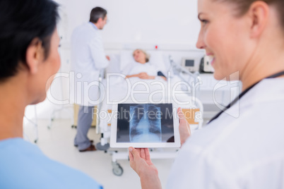 Doctors examining x-ray with blurred patient in background