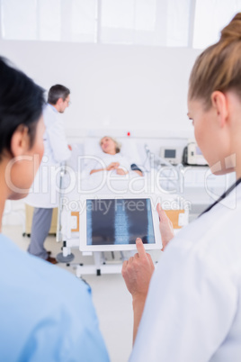 Doctors examining x-ray with blurred patient in background