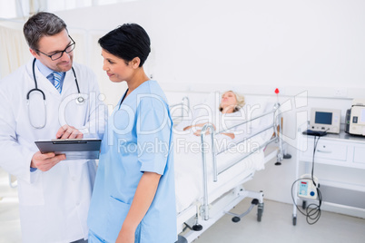 Doctors discussing reports with patient in background