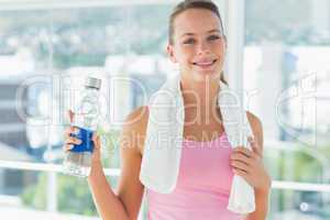 Woman with towel and water bottle in gym
