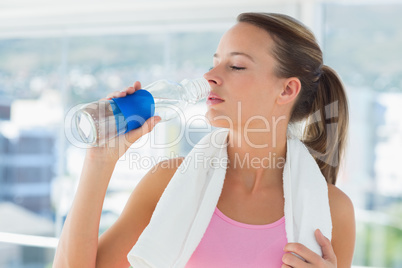 Young woman drinking water in gym