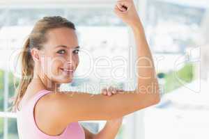 Young woman flexing muscles in gym