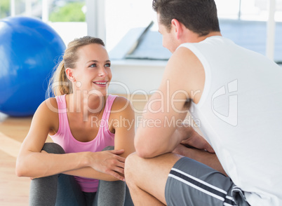 Smiling fit couple chatting in exercise room