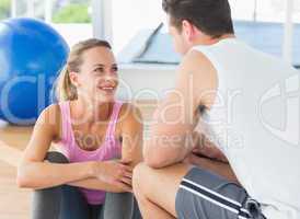 Smiling fit couple chatting in exercise room