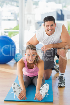 Male trainer assisting young woman with pilate exercises