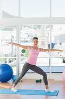 Sporty young woman stretching hands in fitness studio