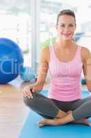 Smiling young woman sitting at fitness studio