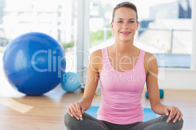 Smiling young woman sitting at fitness studio