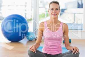 Smiling young woman sitting at fitness studio