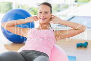 Smiling woman exercising on fitness ball at gym