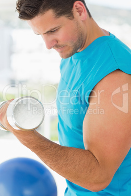 Sporty young man with dumbbell in gym