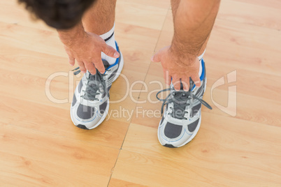 sporty man stretching hands to legs in fitness studio