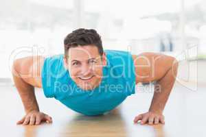 Portrait of a smiling young man doing push ups