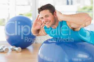 Young man exercising on fitness ball at gym