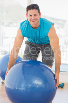 Smiling man exercising with fitness ball at gym