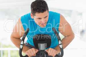 Serious man working out at spinning class