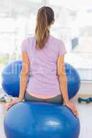 Fit young woman sitting on exercise ball at gym