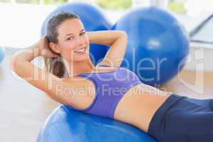 Side view portrait of a smiling fit woman lying on exercise ball