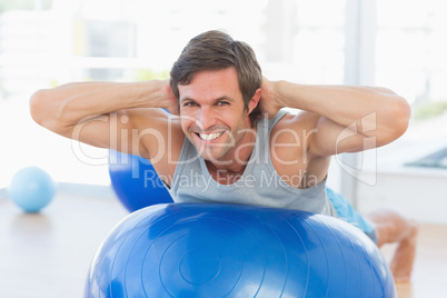 Happy fit man stretching on exercise ball