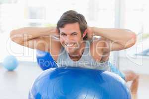 Happy fit man stretching on exercise ball