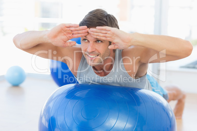 Happy fit man stretching on exercise ball