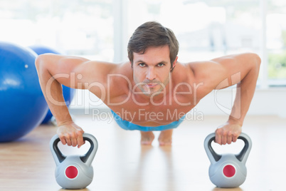 Serious young man doing push ups in gym