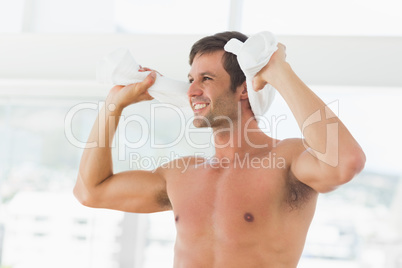 Smiling shirtless man with towel in gym