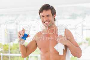 Shirtless young man with towel drinking water