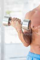 Mid section of a sporty young man with dumbbell