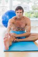 Sporty young man stretching hand to leg