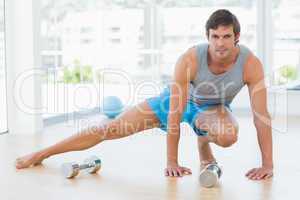 Sporty man doing stretching exercise in fitness studio