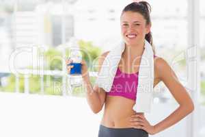 Fit woman with towel and water bottle in gym