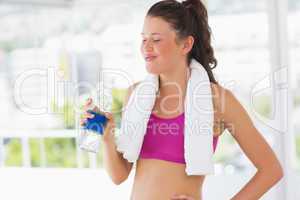 Fit woman with towel drinking water in gym