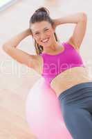 Smiling fit woman exercising on fitness ball at gym