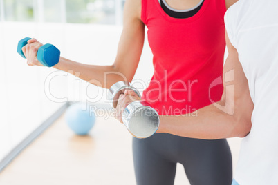 Mid section of a sporty couple with dumbbells