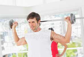 Young fit man lifting the barbell