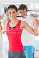 Fit young man and woman lifting barbells