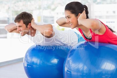 Fit couple exercising on fitness balls in gym