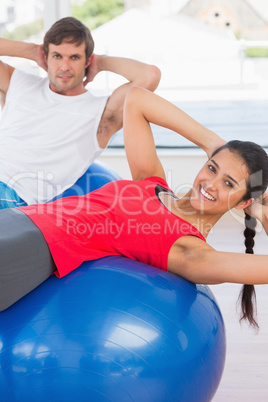 Fit couple exercising on fitness balls in gym