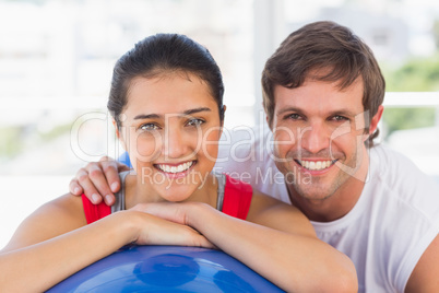 Smiling fit couple with exercise ball at gym