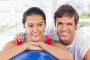 Smiling fit couple with exercise ball at gym