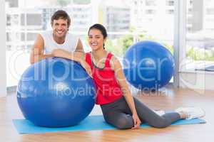 Smiling fit young couple with exercise ball at gym