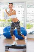 Fit young woman performing step aerobics exercise