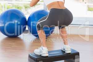 Low section rear view of a fit woman exercising on step