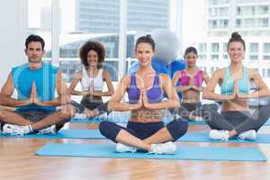 People in Namaste position smiling at fitness studio