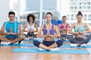 People in Namaste position with eyes closed at fitness studio