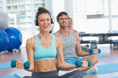 Fit people listening to music while lifting dumbbell weights