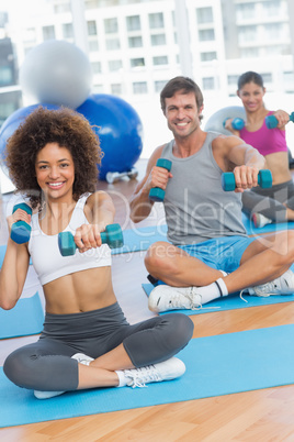 Portrait of a fit class lifting dumbbell weights